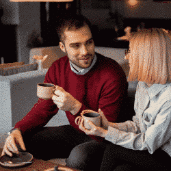 Kobieta i mężczyzna rozmawiający w salonie z kubkami kawy w ręce. Fundacja dla Rodziny