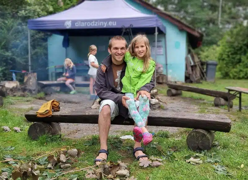 tata z córką na kolanach na biwaku