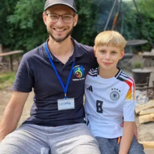 Tata obejmujący syna. Obaj siedzą na ławce.
