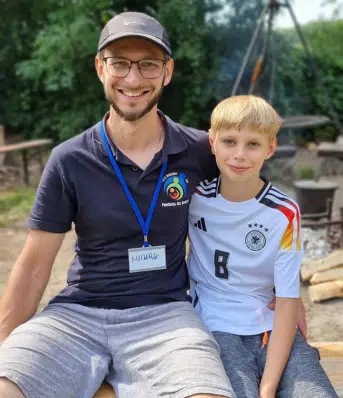 Tata obejmujący syna. Obaj siedzą na ławce.