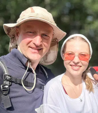 Tata obejmuje córkę ramieniem.
