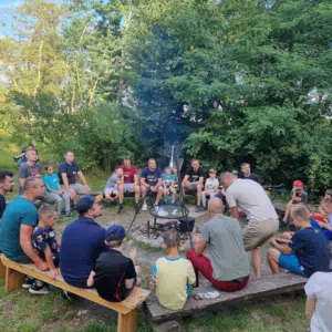 ojcowie i dzieci siedzący wokół ogniska