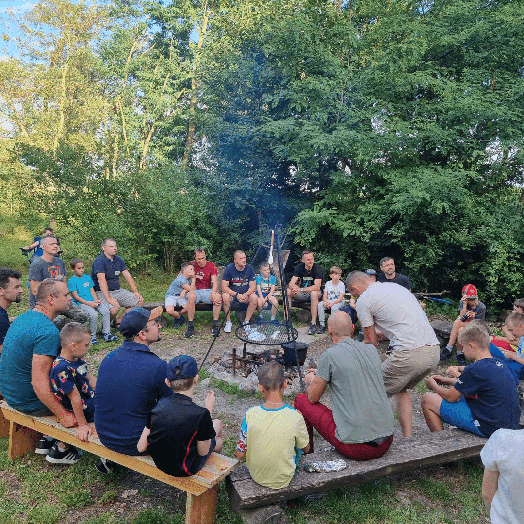 ojcowie i dzieci siedzący wokół ogniska