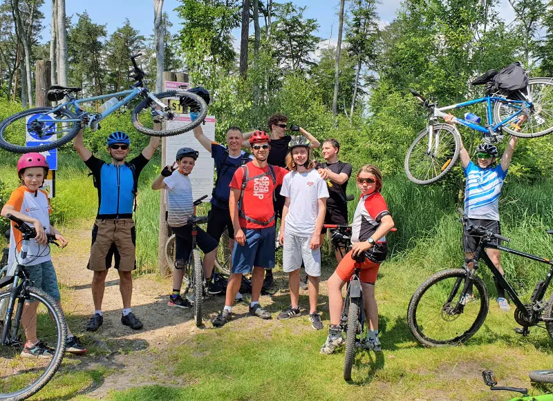 grupa ojców z nastolatkami na rowerach w lesie