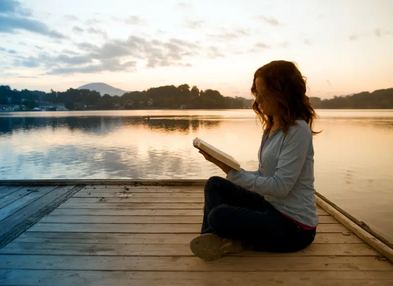 Kobieta czytająca Biblię na pomoście.