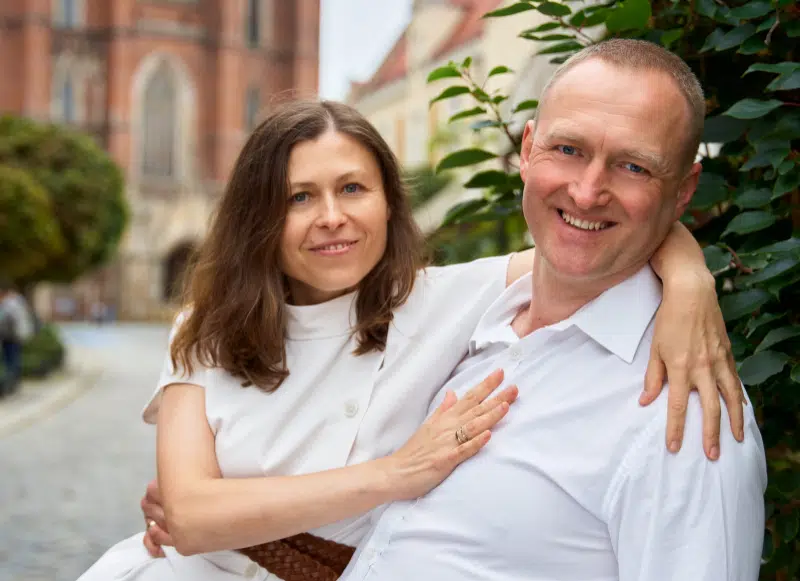 Małżeństwo. Kobieta siedzi na kolanach męża i obejmuje go ramieniem.