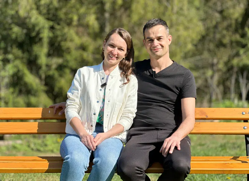 Małżeństwo siedzi na ławce i przytula się.