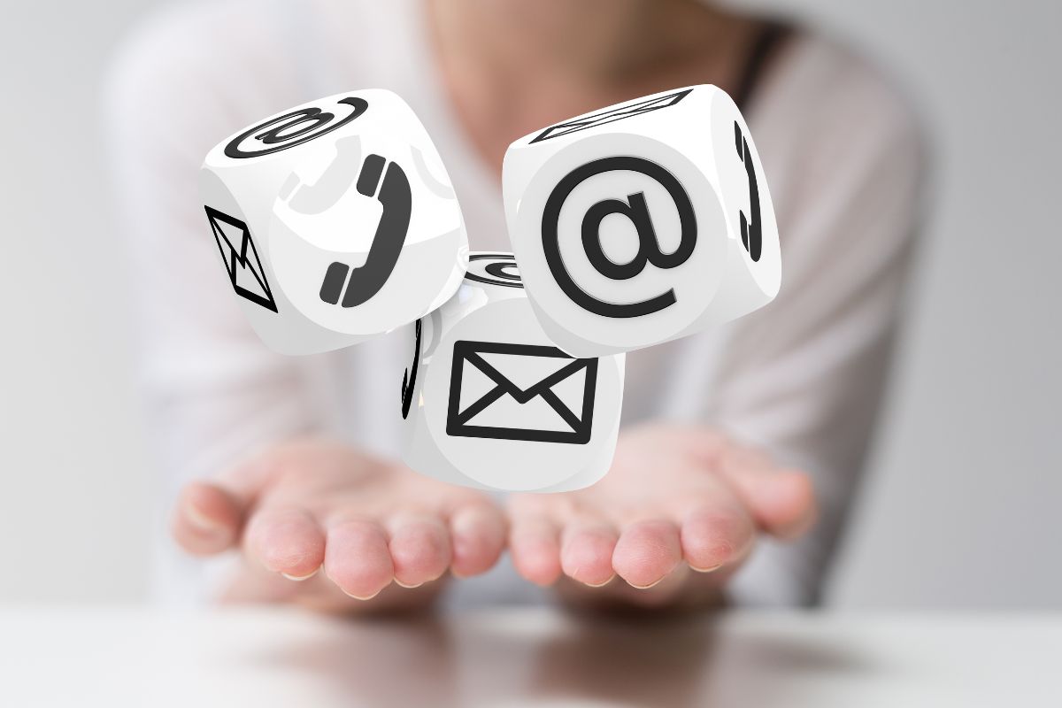 Osoba trzyma unoszące się kostki z symbolami kontaktu: telefon, e-mail, list.