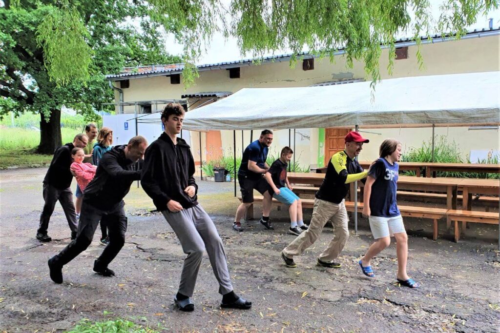 Grupa osób bawi się na świeżym powietrzu, uśmiechnięci uczestnicy zebrani w szeregu.